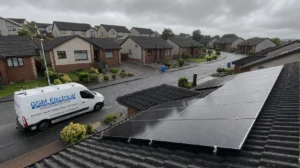 A GSM Electrical engineer beside a solar panel installation on a cloudy Scottish day. Solar Panel Cost Comparison. Solar Panels in Edinburgh.